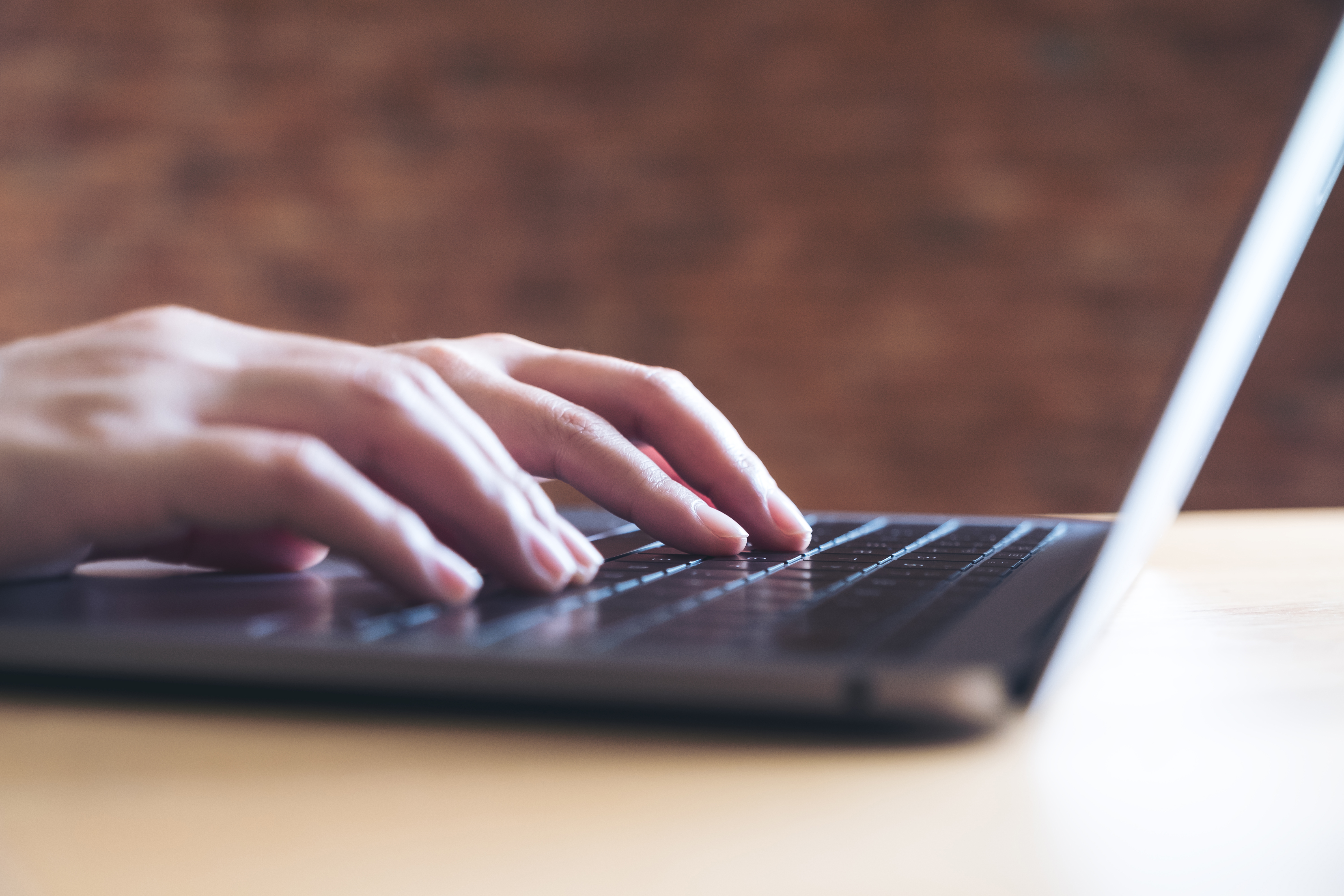 Closeup image of hands working and typing on laptop keyboard in